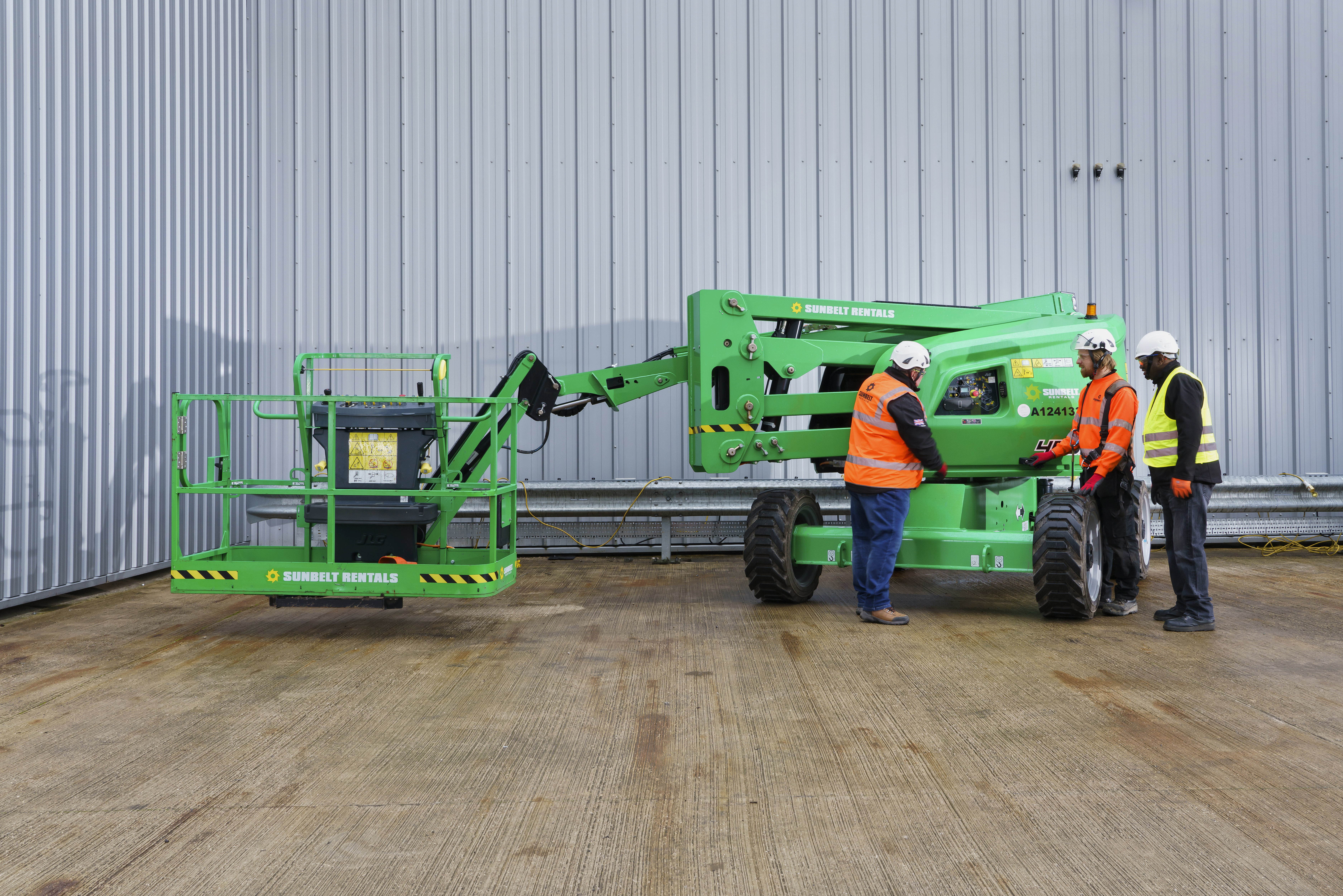 three operators inspecting a boom lift on a Sunbelt Rentals depot
