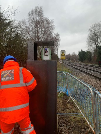 Smarttrax rail operative working by railway line with Sunbelt Rentals Survey total station